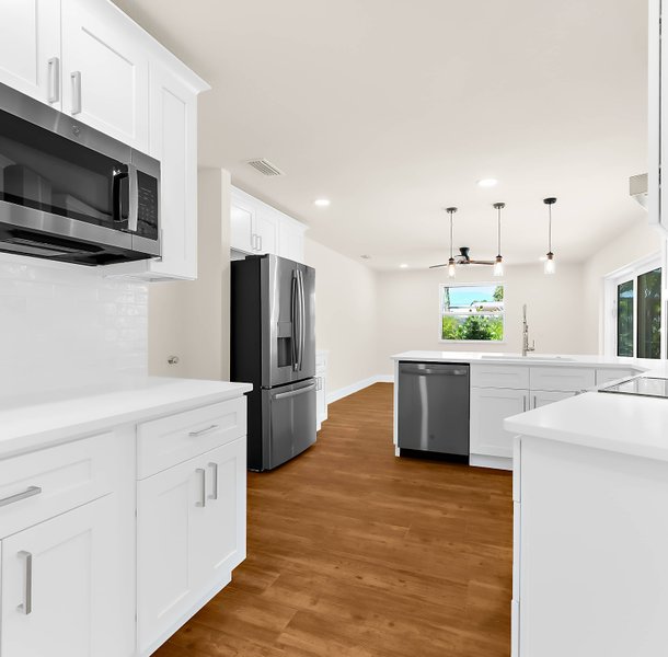 Bright white kitchen with island, stainless appliances, pendant lights